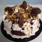 ice cream cake toppedw ith peanut butter cups, chocolate drizzle and peanut butter syrup